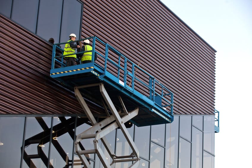 builder on a scissor lift platform at a construction site. men at work