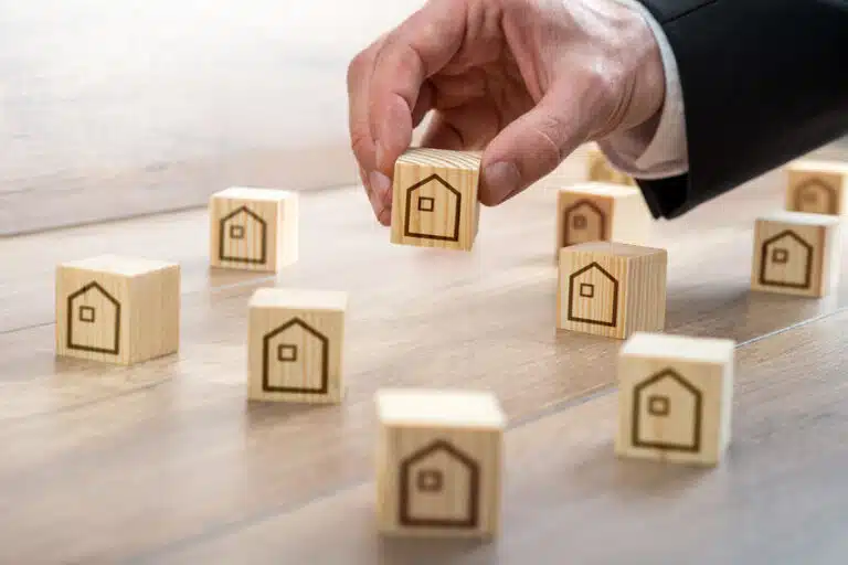 man arranging wooden cubes with house drawings